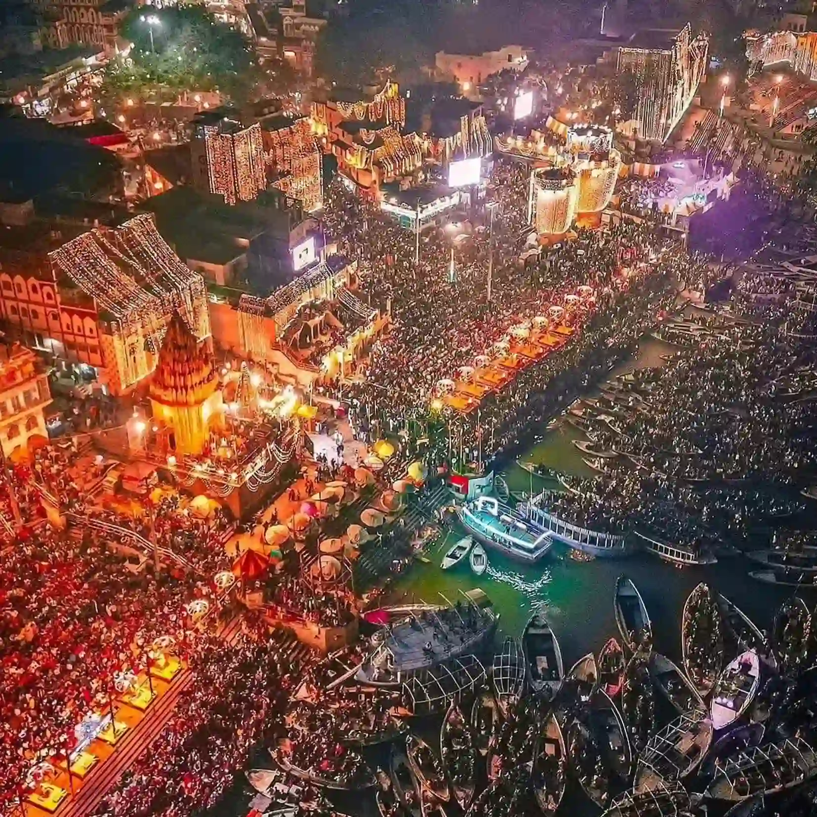 Aerial view of visitors gathering beside the brightly illuminated ghats for Dev Diwali